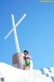 A woman in a bikini standing next to a large white cross.