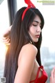 A woman with long black hair wearing a red bunny ears headband.