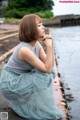 A woman sitting on the edge of a body of water.