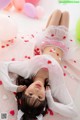 A woman laying on the floor surrounded by balloons and hearts.